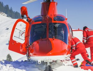 Rescue helicopter landed on a snowy mountainside with two emergency responders