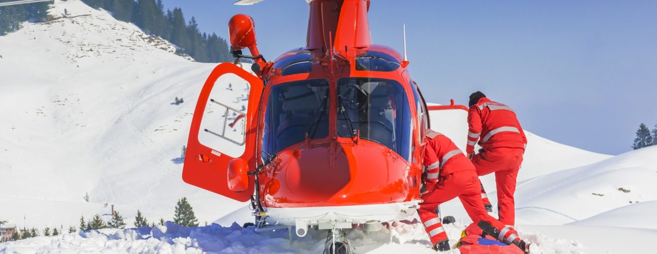 Rescue helicopter landed on a snowy mountainside with two emergency responders