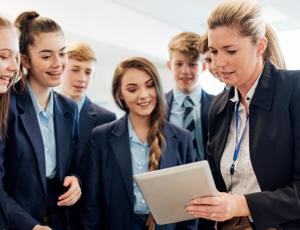 Group of students gathered around another person holding a tablet during a lab activity