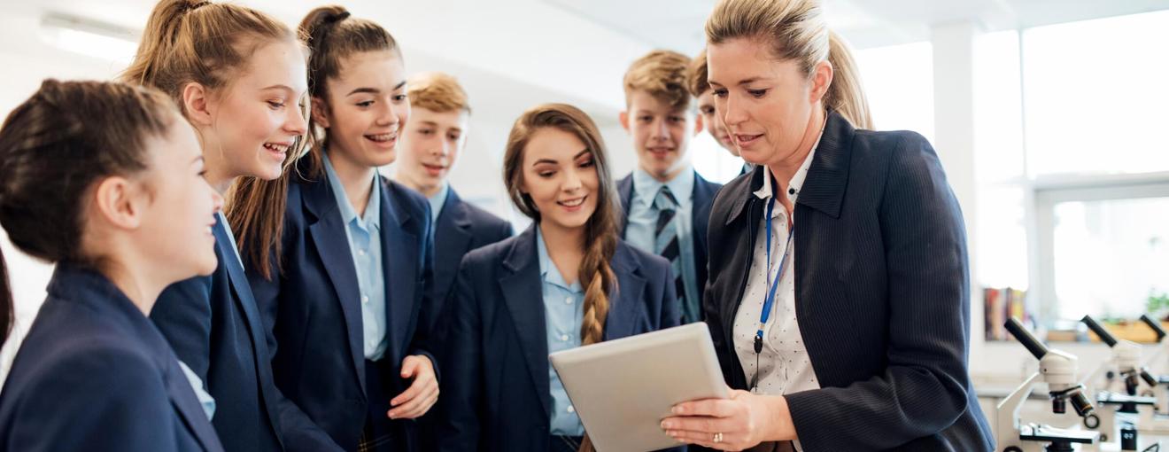 Group of students gathered around another person holding a tablet during a lab activity