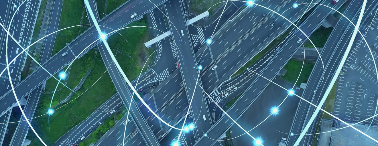 Aerial view of a motorway interchange, overlaid with glowing digital network lines